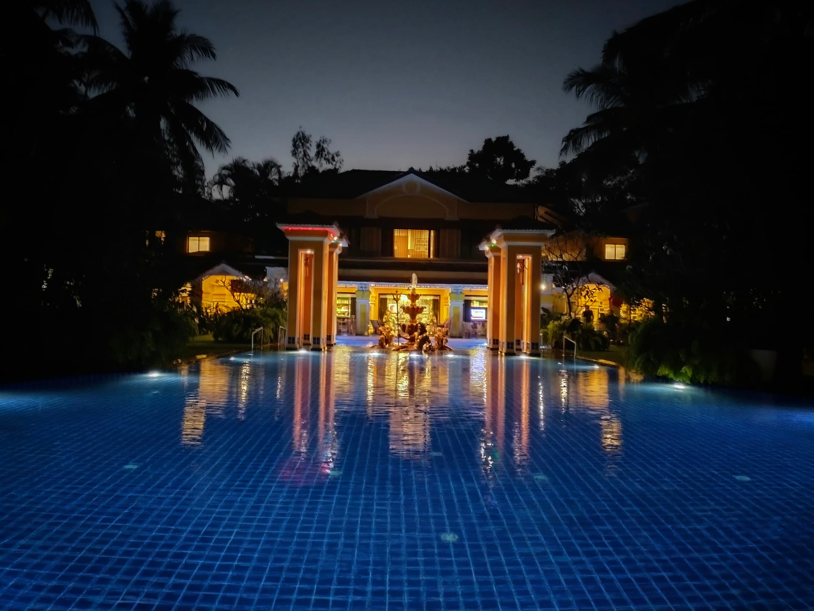 The same kind of residence at night, its pool lit gold